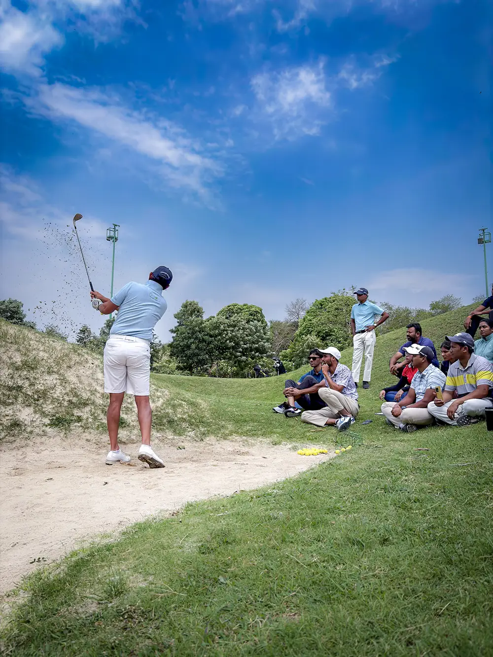 Bunker shot in front of attentive golfers